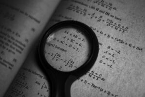 A magnifying glass focuses on mathematics formulas in a book, enhancing study and exploration.