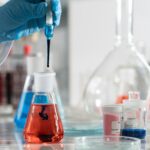 Scientist conducting a laboratory experiment with colorful chemical solutions and scientific glassware.